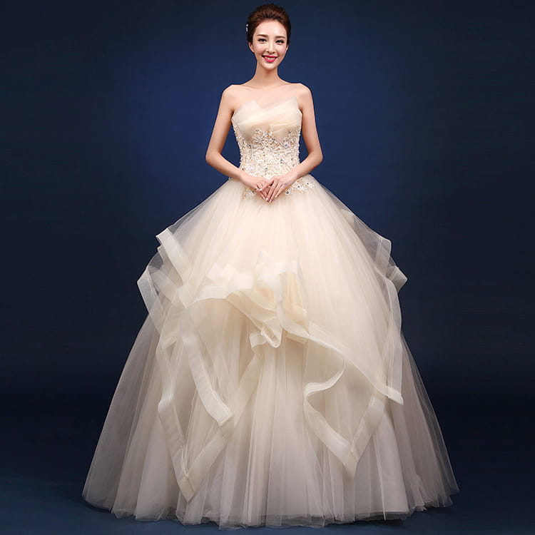 A strapless ivory wedding dress featuring a beaded bodice and layered tulle skirt designed to offer a neatly slim silhouette.