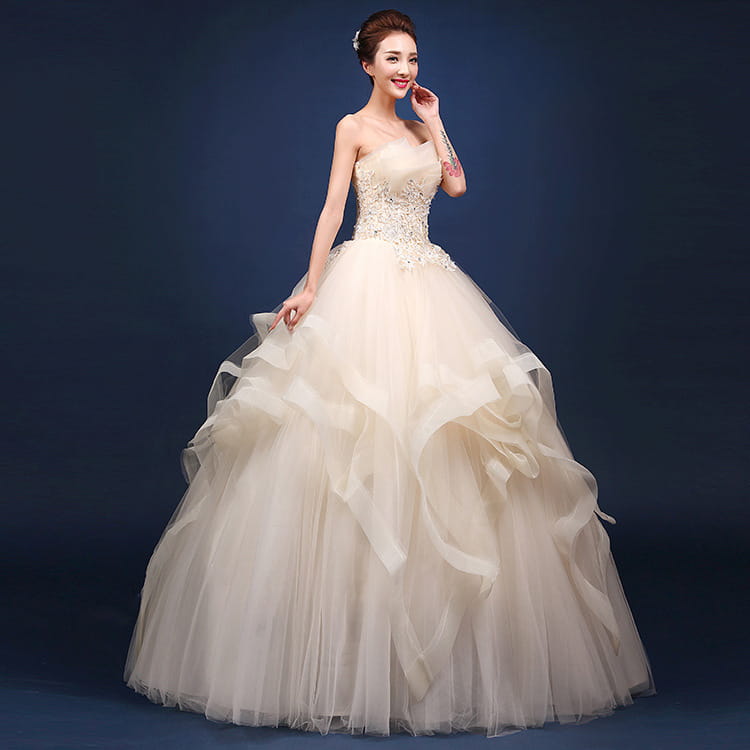 A strapless ivory wedding dress with a beaded bodice and layered tulle skirt designed to offer a neatly slim fit, complementing one-shoulder wedding dresses.