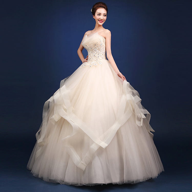 Beige strapless ball gown wedding dress with intricate beading on the bodice and layered tulle skirt designed for a neatly slim silhouette in one-shoulder wedding dresses collection.