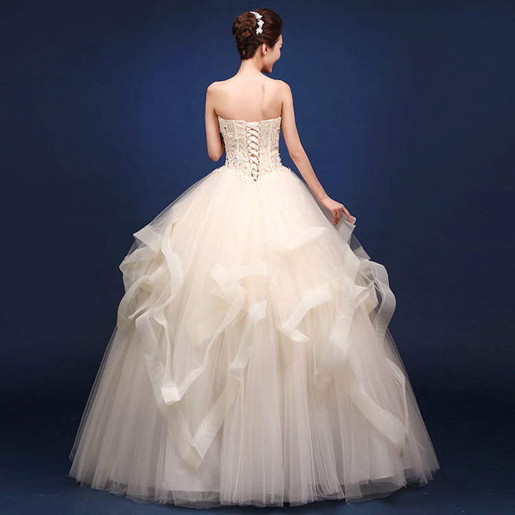 a strapless ivory wedding dress with a lace-up corset back and layered tulle skirt showcasing the back side of the neatly slim design not featuring the one-shoulder wedding dresses style
