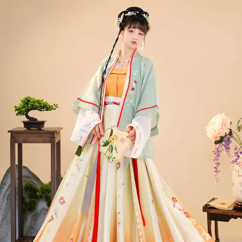 A woman wears a flowing light green and cream han chinese clothing summer outfit featuring intricate floral embroidery along the sleeves and hem for clothing summer improvement.