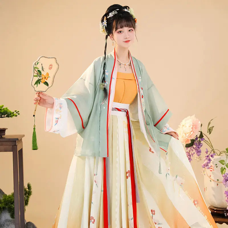 A woman wears a delicate light green and cream-colored han chinese clothing summer embroidered hanfu with red trim detailing for clothing summer improvement.