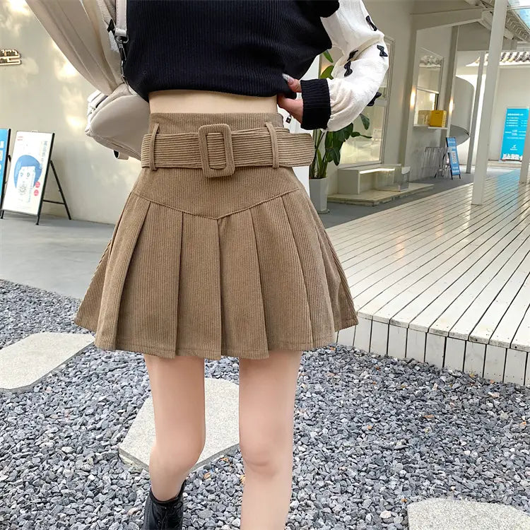 Tan corduroy half skirt pleated mini with a matching brown belt featuring a rectangular buckle and pleated skirt design.