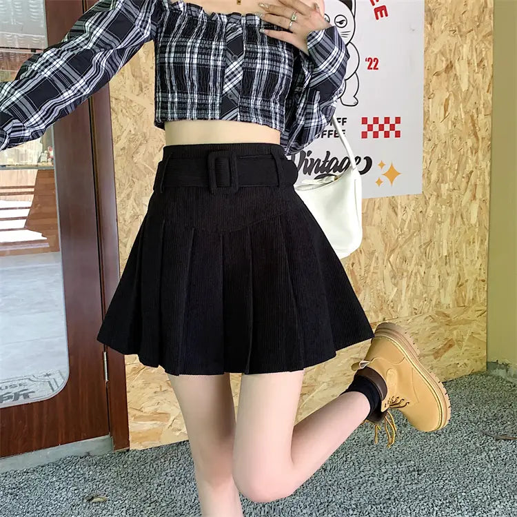 black corduroy pleated mini skirt with a wide brown belt and rectangular buckle in a half skirt pleated style