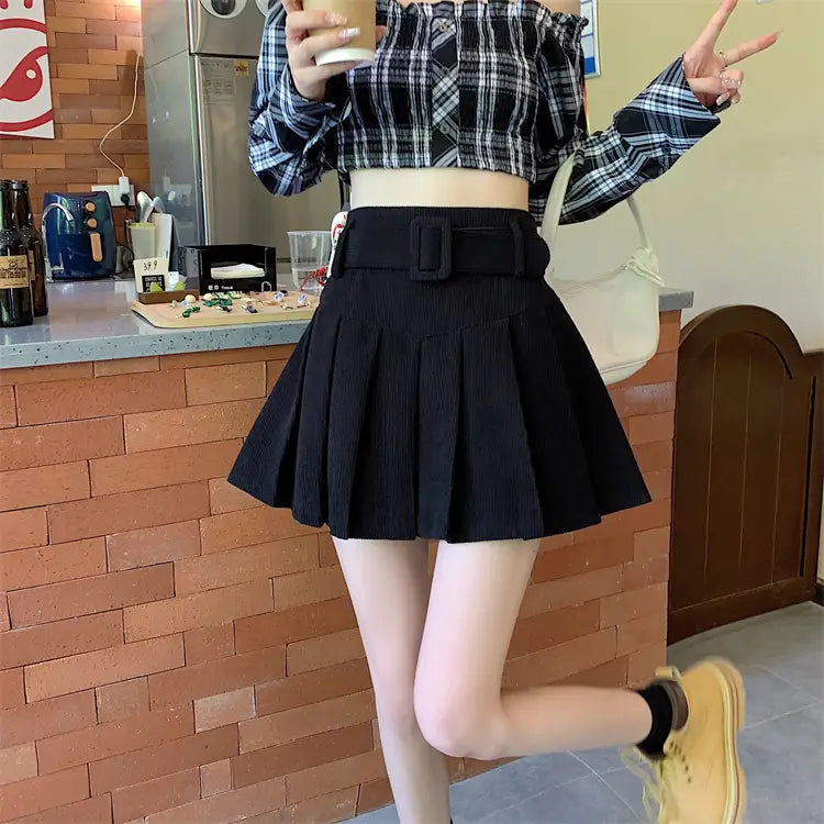 black pleated corduroy half skirt featuring a wide brown belt with a rectangular buckle