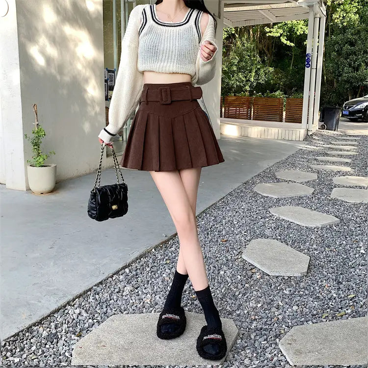 brown corduroy half skirt pleated mini with a wide belt paired with a black chain-strap handbag