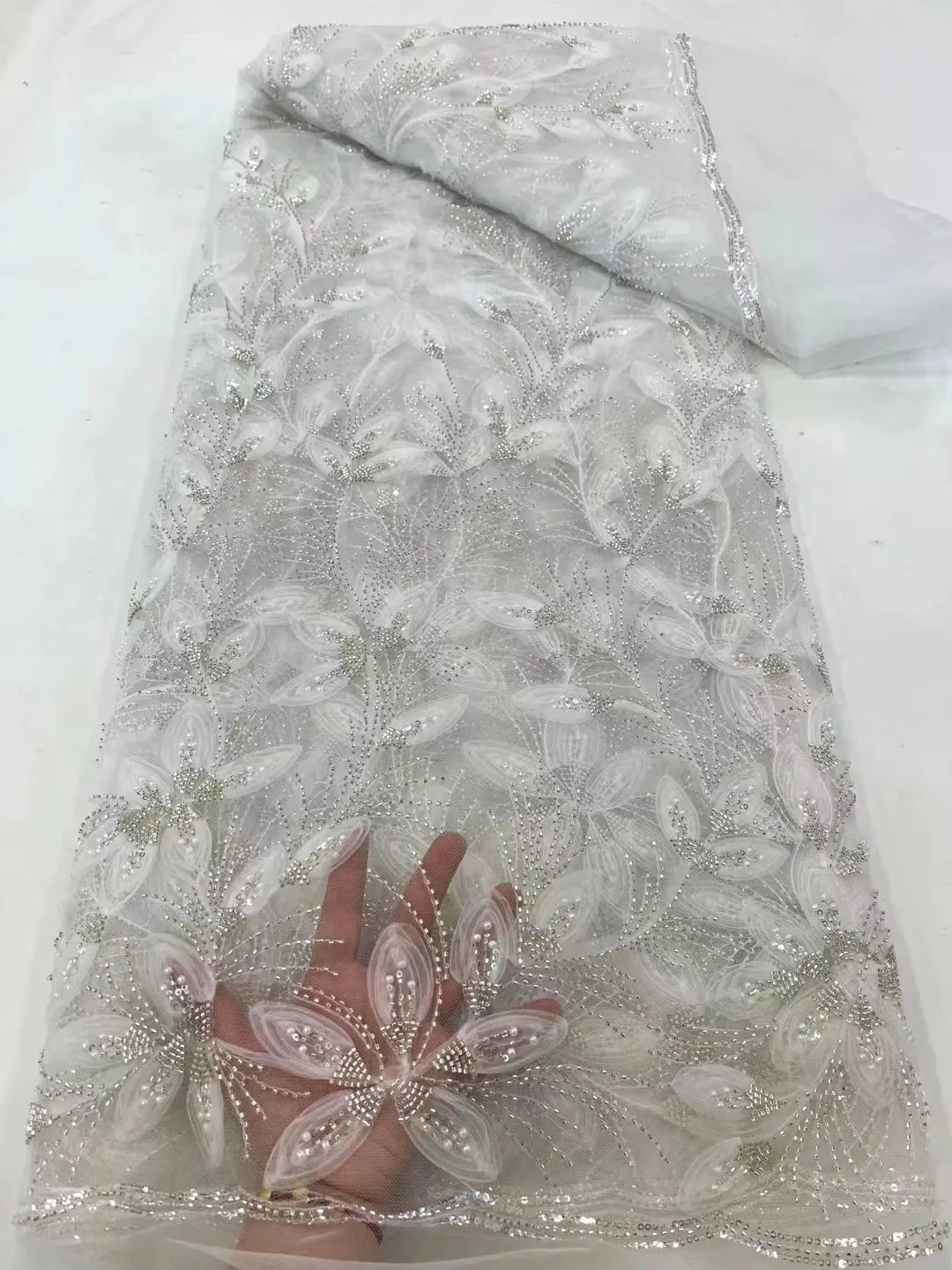 a delicate sheer white beaded tulle lace fabric with intricate silver ribbon flower beaded embroidery and floral patterns