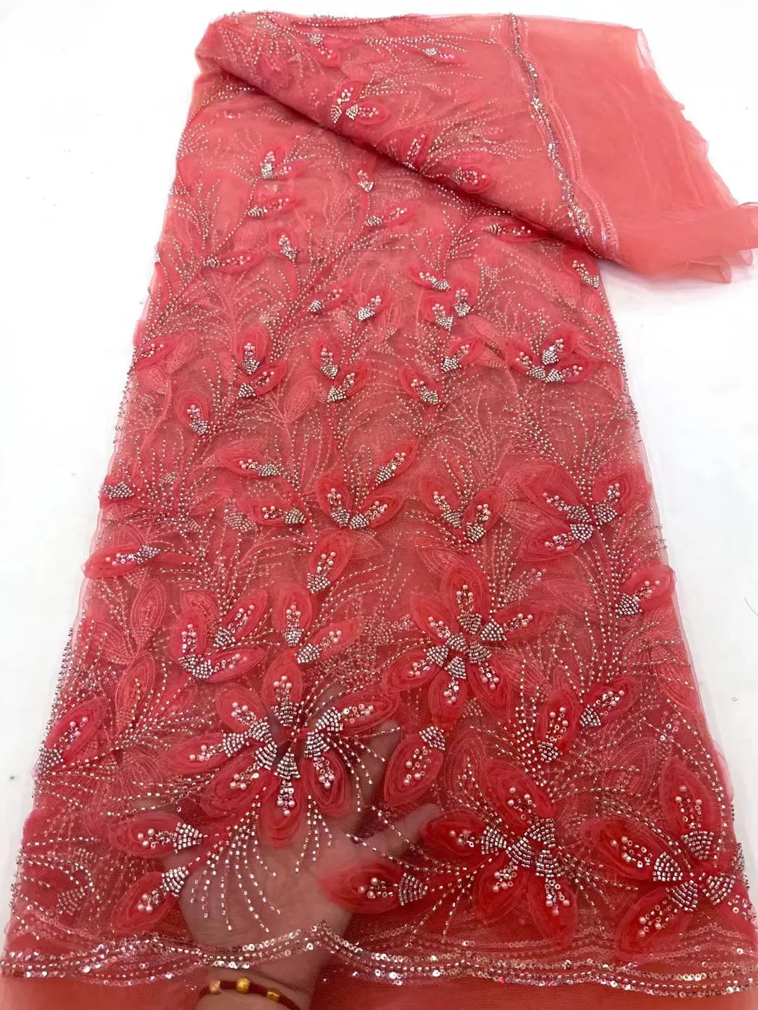 A vibrant coral-colored peach ribbon flower beaded tulle lace fabric featuring intricate floral appliqués and sparkling silver beading.