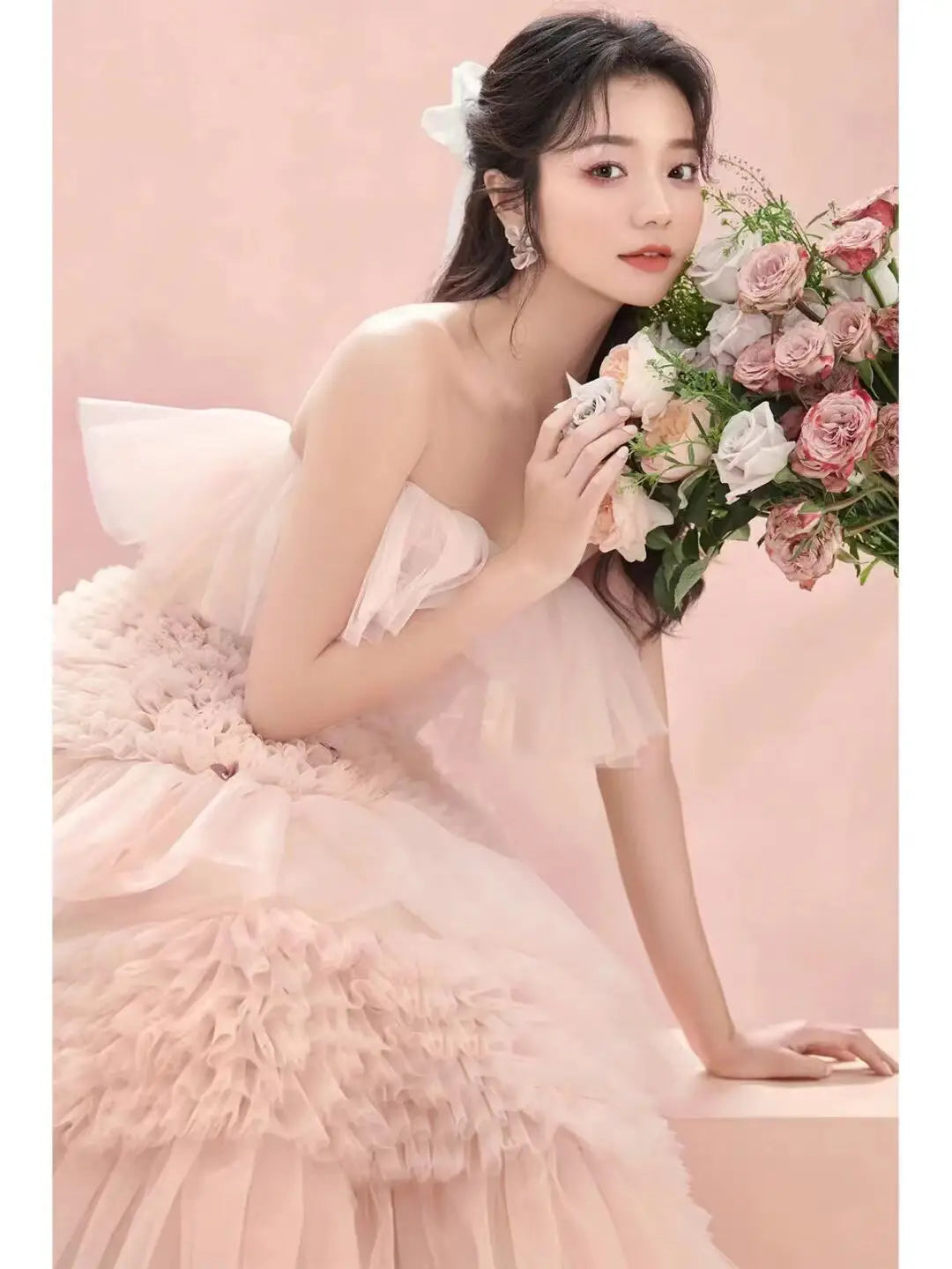 A delicate strapless blush pink photography pettiskirt colored mesh dress with layered ruffles and a soft flowing silhouette.