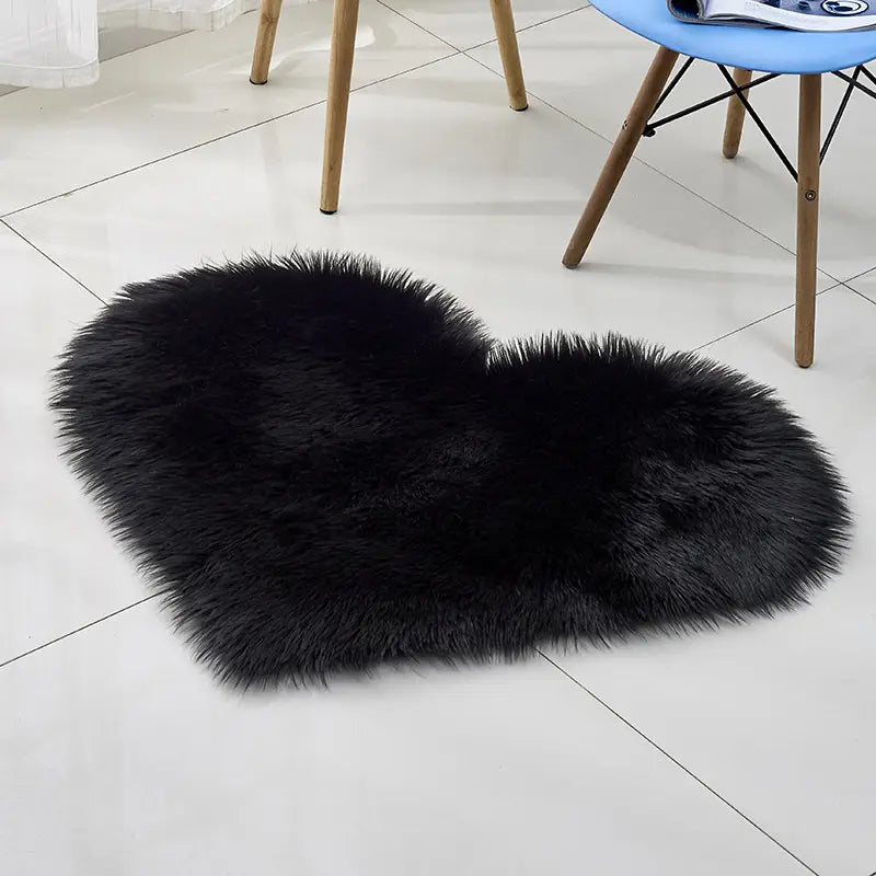 Black heart shaped faux fur rug showcased as a plush heart shaped living room accent contrasting with the mint green plush heart shaped living room rug and sofa cushions.