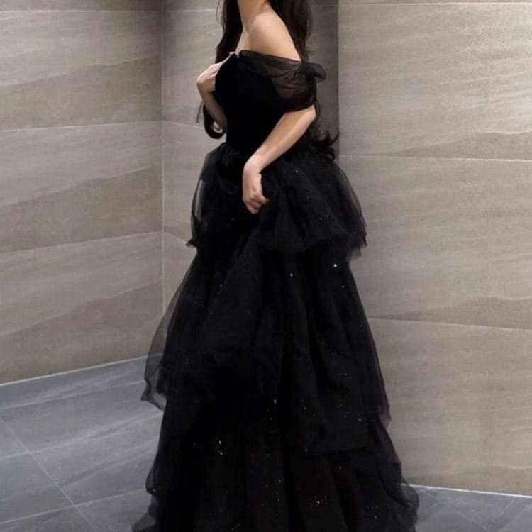Elegant black evening dress featuring an off-the-shoulder design with layered tulle and subtle glitter accents in a dress light luxury evening style.