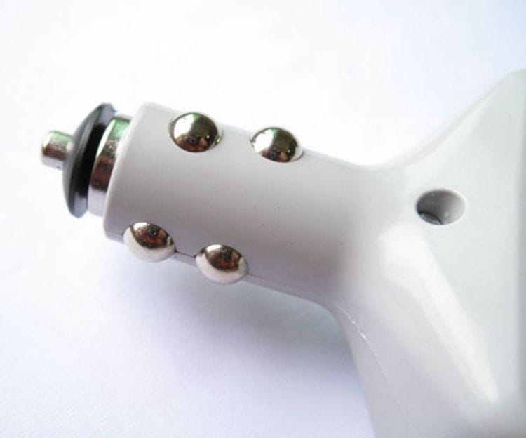 White power supply car transformer with silver metallic studs and black rubberized plug designed for car transformer mobile use with USB ports