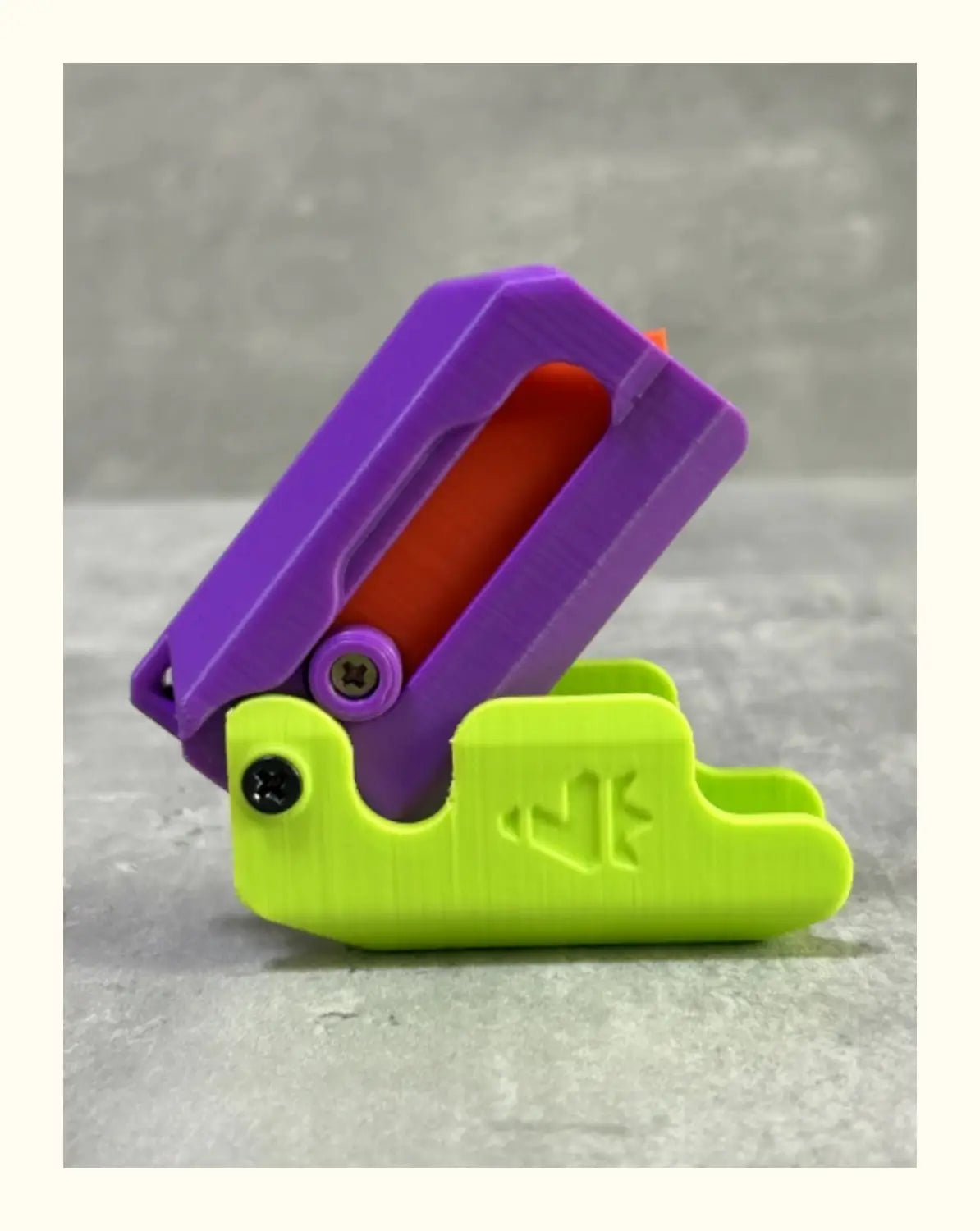 Purple and lime green plastic clip with a red interior component for the pink and lime radish knife printing gravity cub toy.