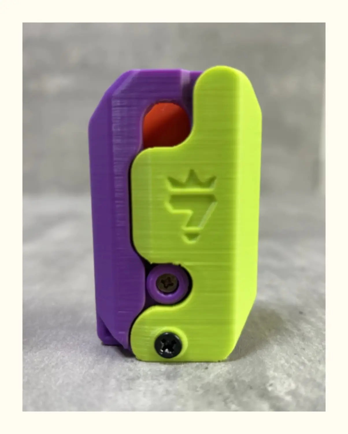 Vibrant purple and neon green 3d-printed dual-tone clip with a crown logo embossed on the front featured in a pink and lime radish knife gravity cub toy for gravity cub jumping.