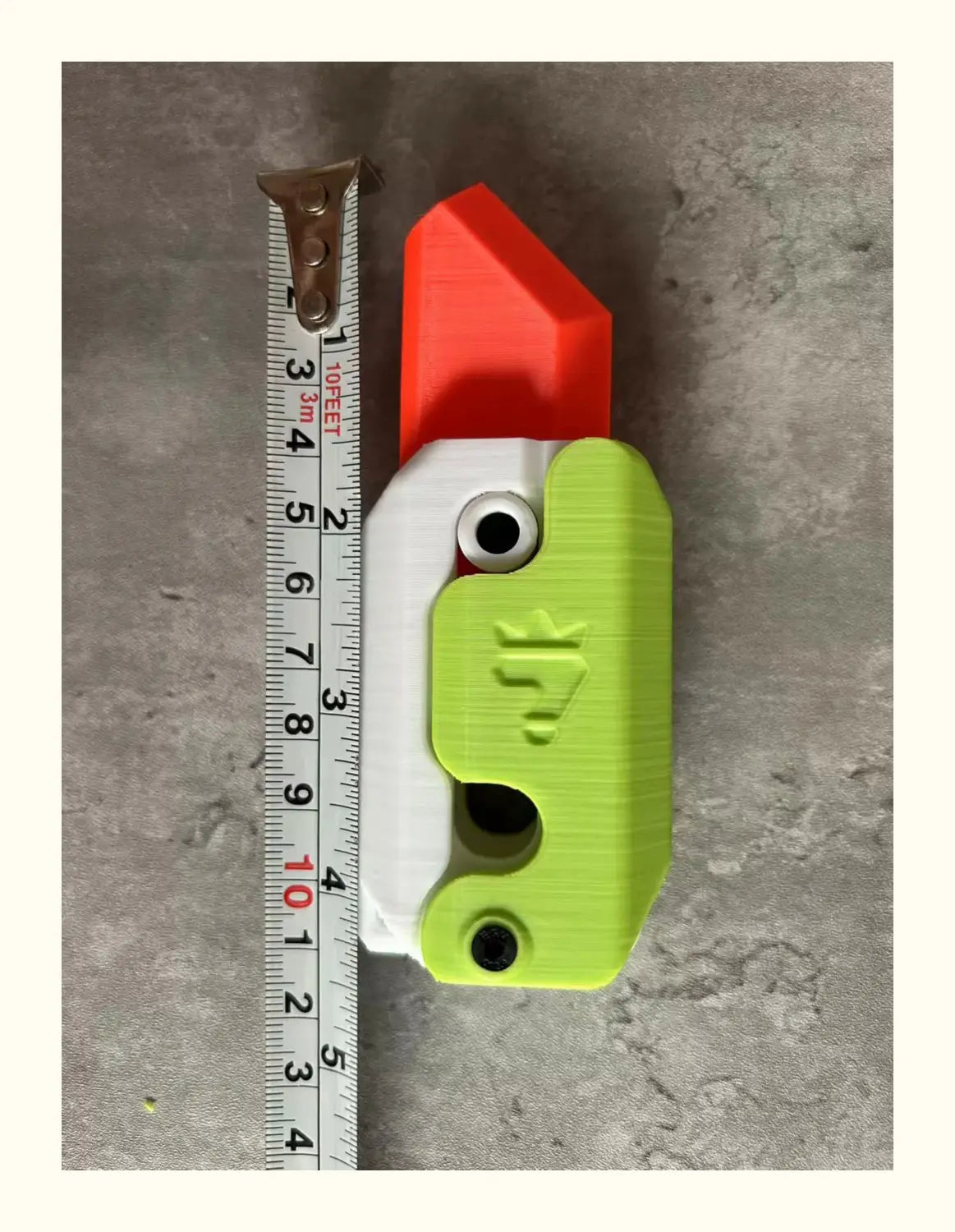 a bright green and white plastic radish knife gravity cub toy with a red top, black circular eyes, and an embossed logo designed for gravity cub jumping and printing gravity cub activities
