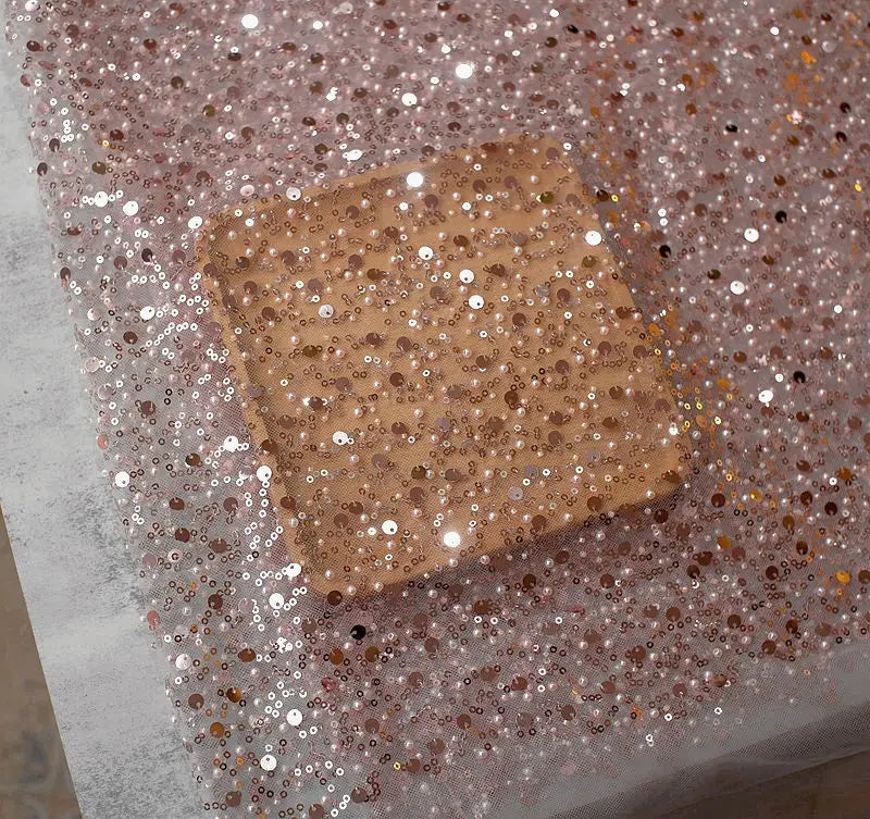a square-shaped compact mirror with a rose gold finish and densely packed sequins complementing the sequined pearl embroidery lace asymmetric dress