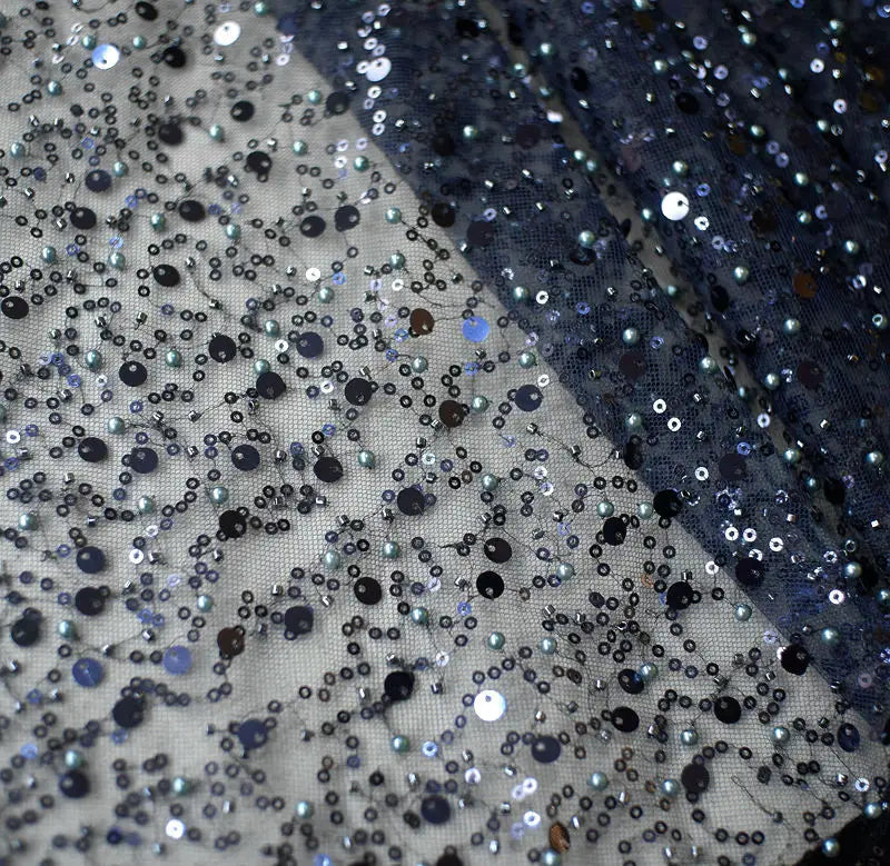 a shimmering navy blue and silver sequined pearl embroidery lace fabric with a sheer mesh base featured in a sequined pearl embroidery lace asymmetric dress