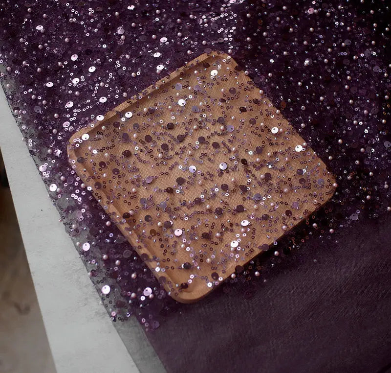 a square light brown wooden tray decorated with dense shimmering purple and silver sequined pearl embroidery lace matching the embroidery lace asymmetric dress design