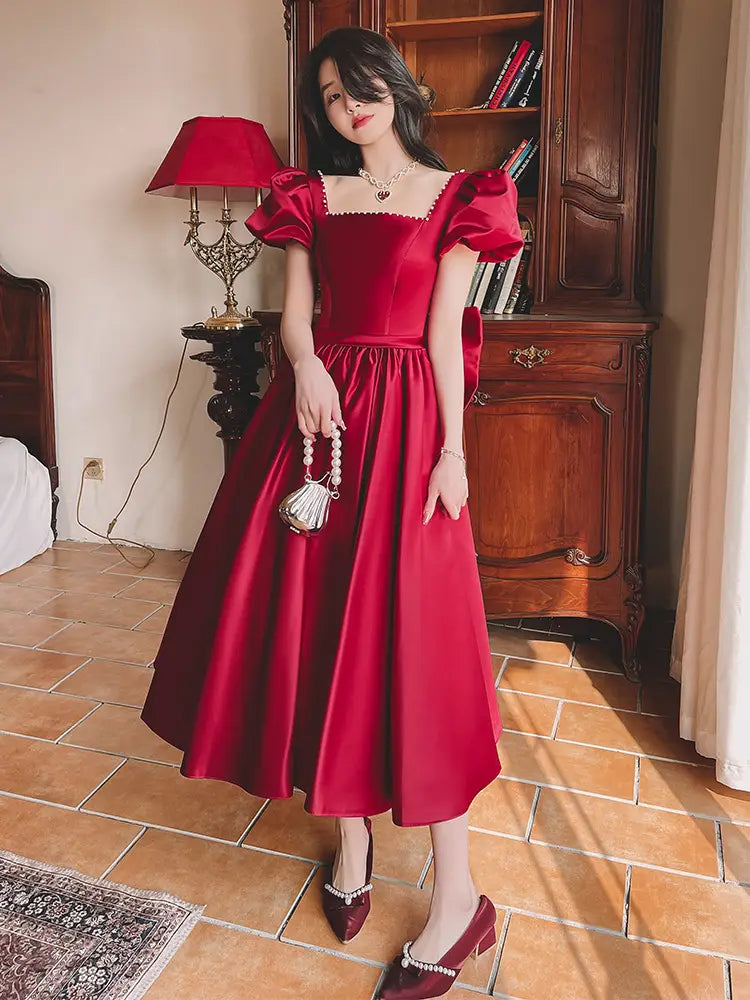 A rich wine red satin midi dress with puffed short sleeves and a square neckline designed for winter wine red engagement occasions.