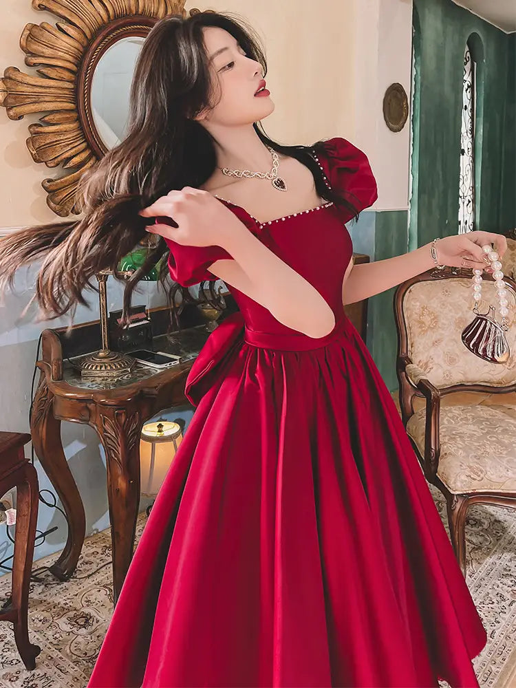 A winter wine red satin engagement dress featuring puffed sleeves and a fitted bodice.