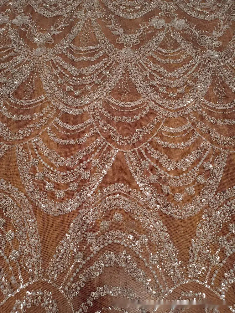 sheer champagne-colored lace fabric for wedding dress adorned with intricate wave style sequin bead lace forming elegant scalloped patterns