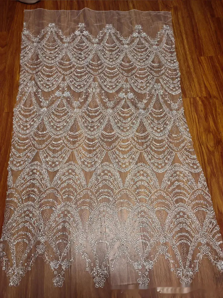 a sheer translucent lace fabric for wedding dress featuring intricate silver sequin bead lace with wave style sequin bead scalloped patterns