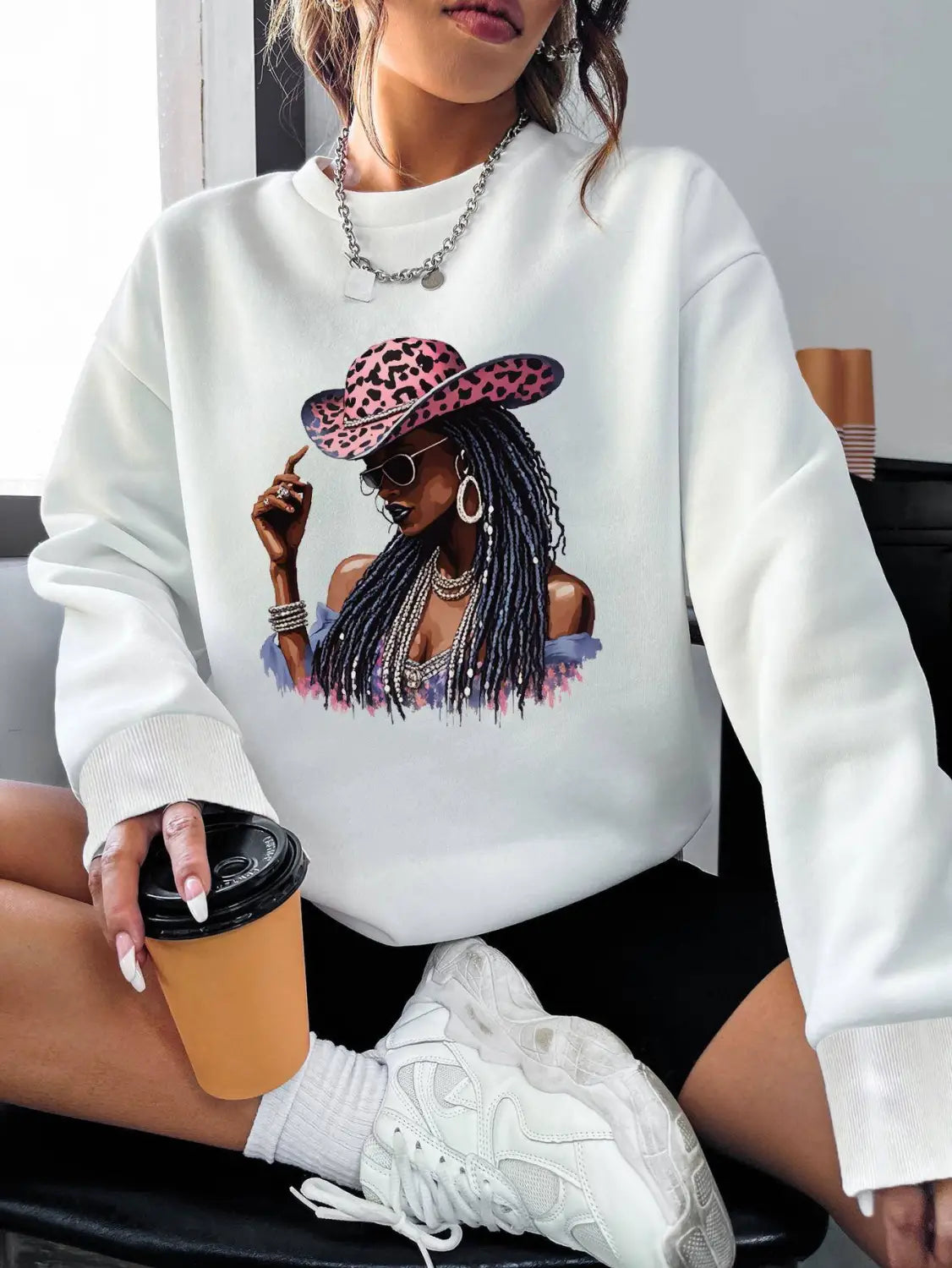 White long sleeve sweatshirt featuring a vibrant graphic of a woman in a pink leopard-print hat and sunglasses.