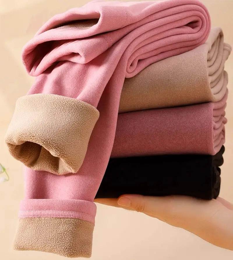 a stack of women’s warm cashmere fleece lined thermal leggings in pastel pink beige and black featuring soft cozy fabric and plush fleece lined cuffs for warm cashmere winter wear