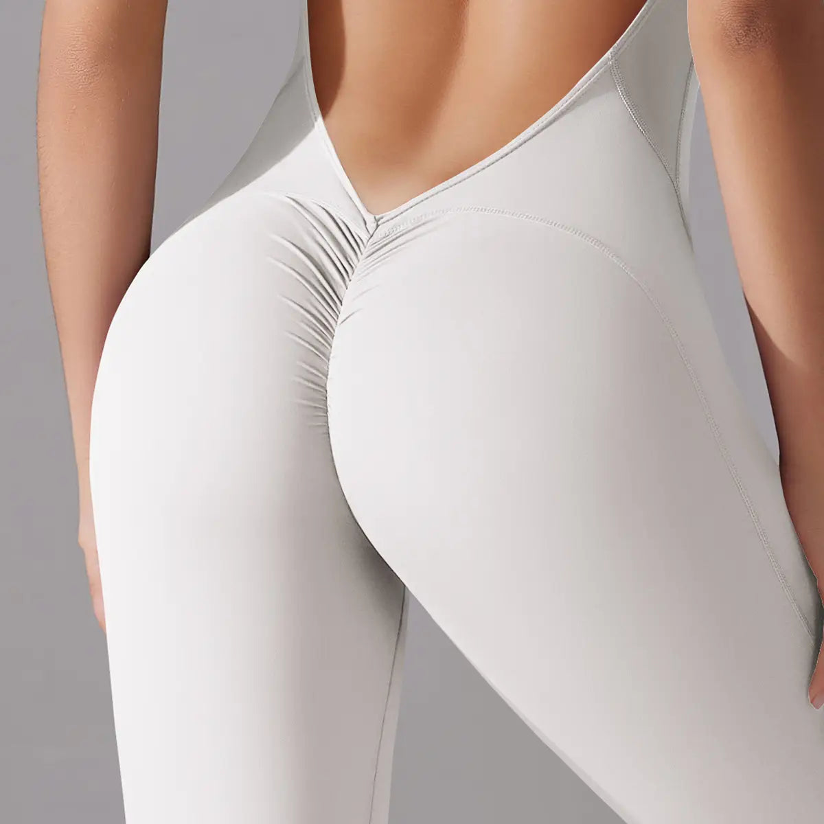 white high-waisted leggings with a ruched back design shown as part of a light blue long pants jumpsuit for yoga fitness use