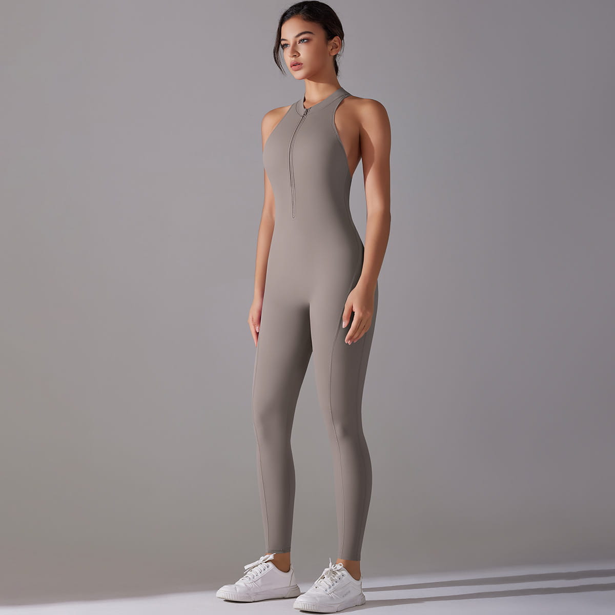 a sleek gray sleeveless athletic one-piece with front zipper and high neckline designed as a pants jumpsuit yoga fitness bodysuit for active wear
