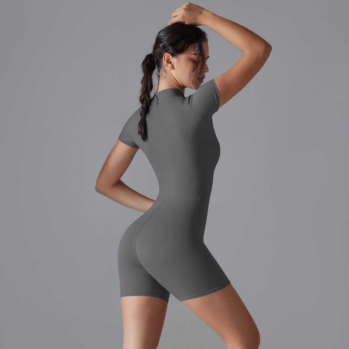 a sleek gray form-fitting shorts jumpsuit yoga bodysuit with short sleeves and a summer zipper designed for athletic use