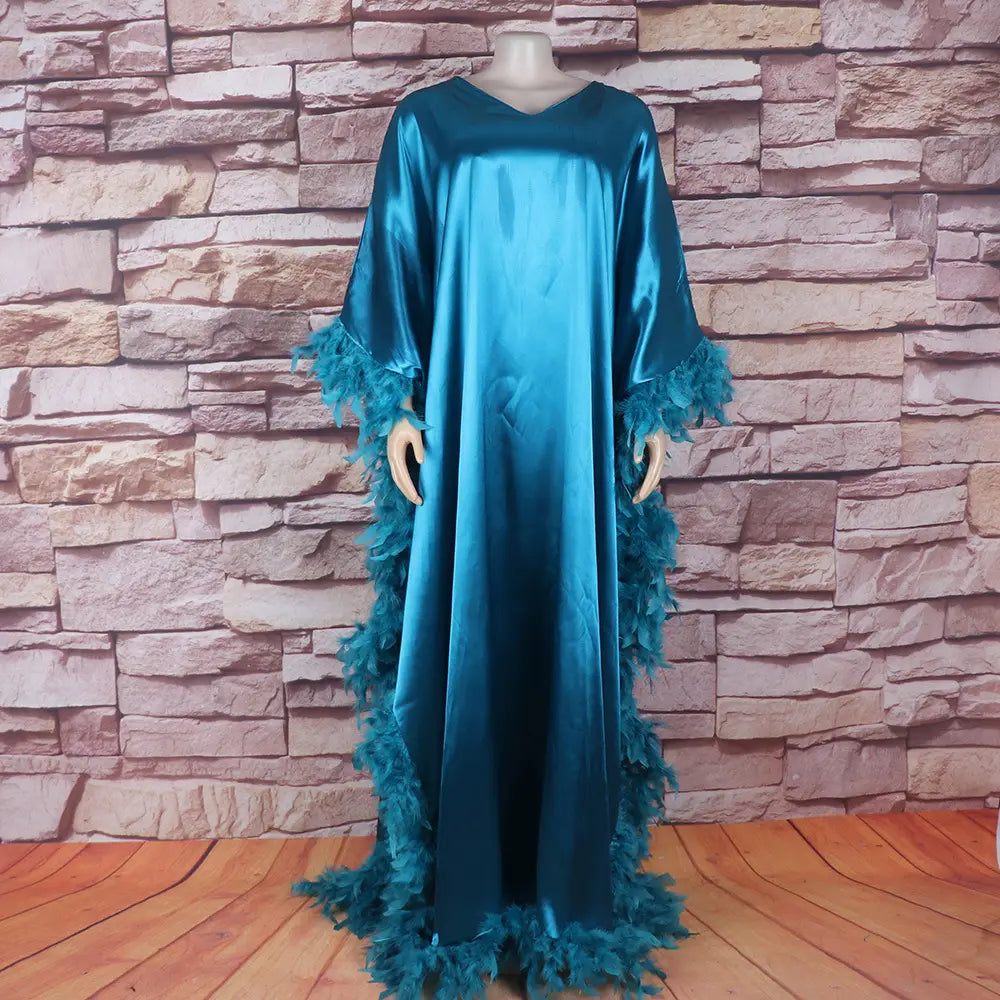 A flowing teal satin loose dress luxury robe with feathered cuffs and hemline designed for a dress luxury fully surrounded style.
