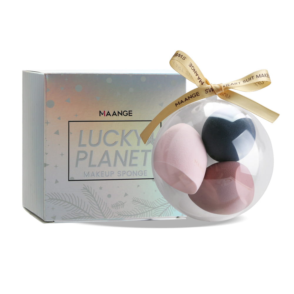 a clear spherical beauty egg gift box tied with a gold ribbon contains three heart-shaped makeup sponges in soft pink black and rose quartz tones
