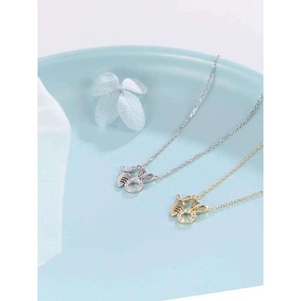 Two delicate rabbit pendant necklaces in 18k gold plated silver and gold with sparkling gemstone accents and carrot detail