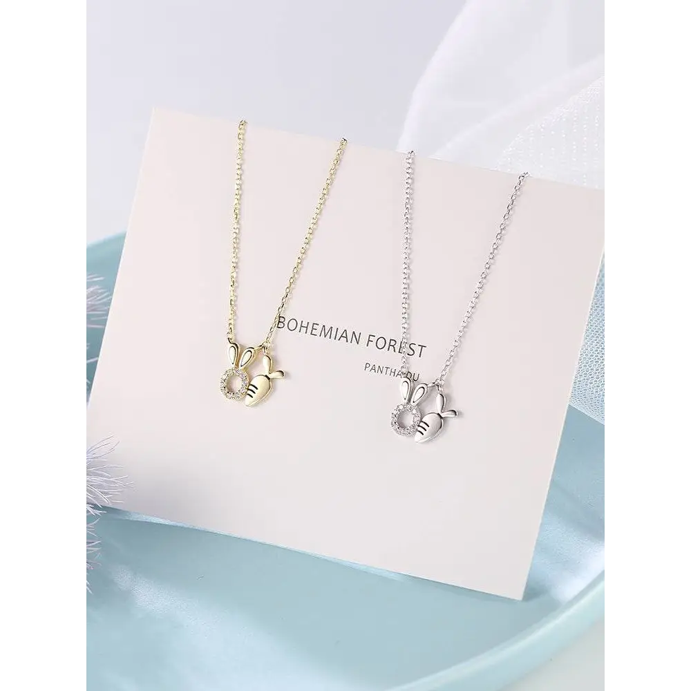 Two delicate 18k gold plated and silver toned rabbit pendant necklaces with crystal embedded charms and carrot detail