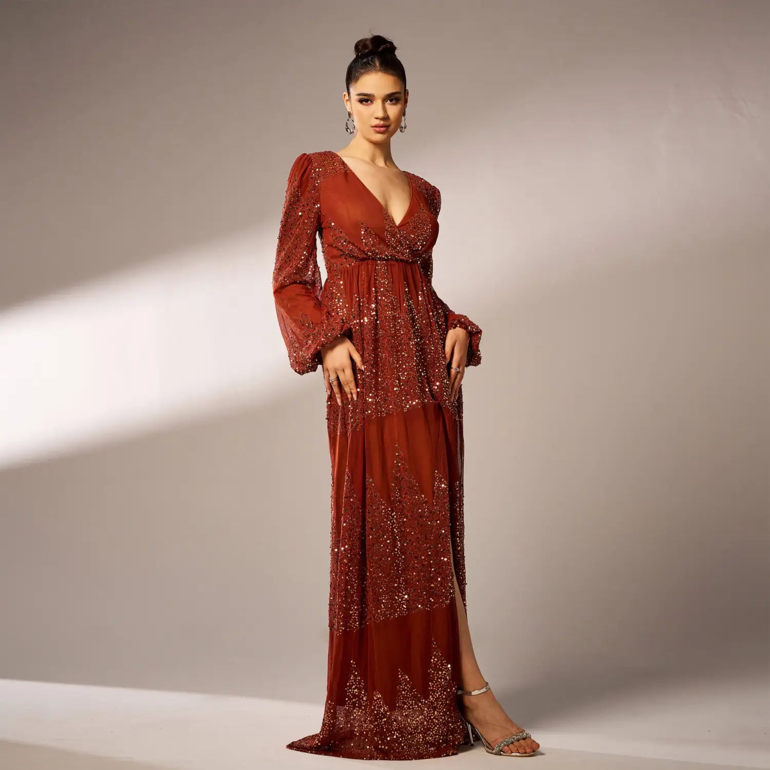 a rust-colored sexy long sequined evening dress featuring long puffy bell sleeves and a deep v-neckline with sparkling sequins along a flowing silhouette