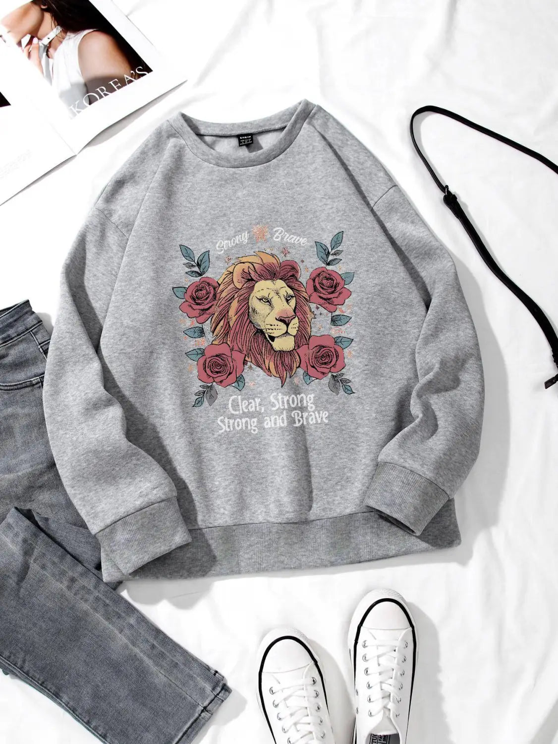gray regular fit long sleeve sweatshirt featuring a detailed lion illustration surrounded by pink roses and the text clear strong brave printed below