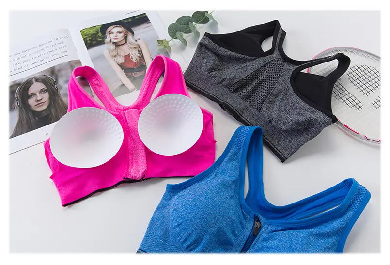 Vibrant pink zipper sports bra with white circular cups and a gray textured front zipper made from breathable fabric for active use.