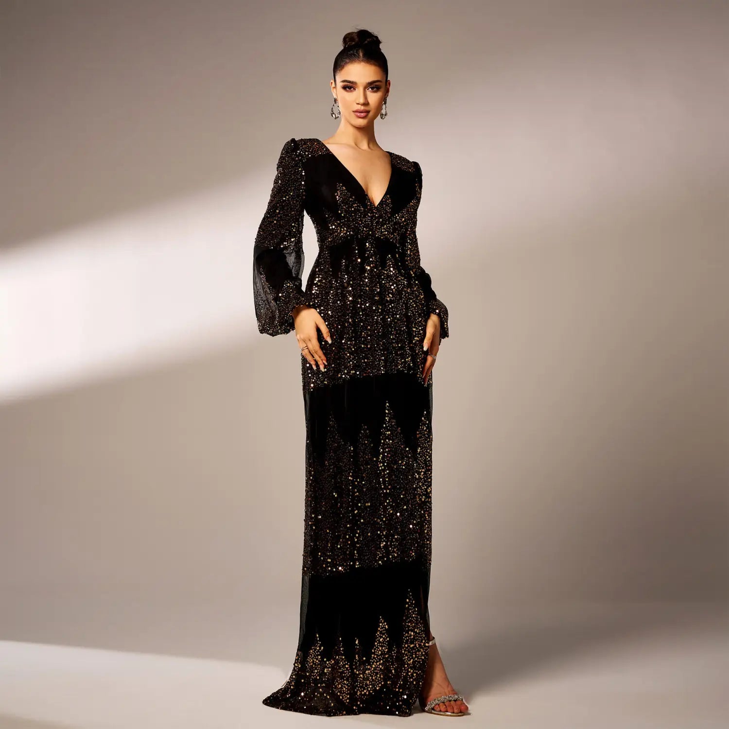 A glamorous black sexy long sequined evening dress featuring a deep v-neckline, long bell sleeves, and cascading sequin embellishments on the bodice and skirt.