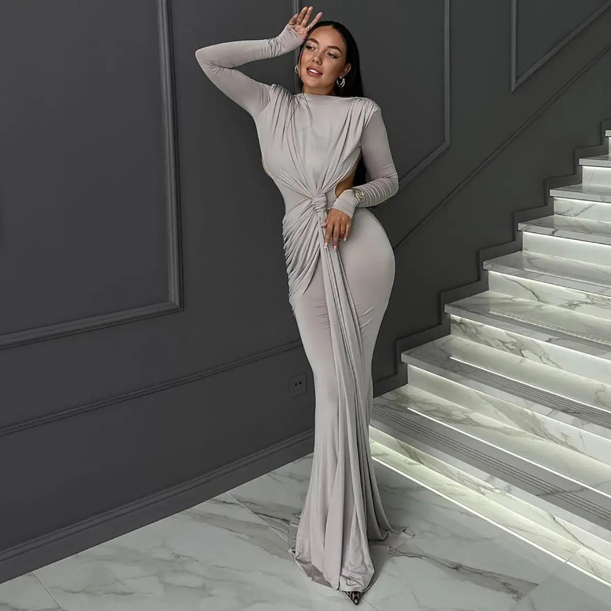A sleek silver-gray form-fitting long sleeve dress with a high neckline and dramatic twisted knot detail at the waist designed for a sexy hot girl look.
