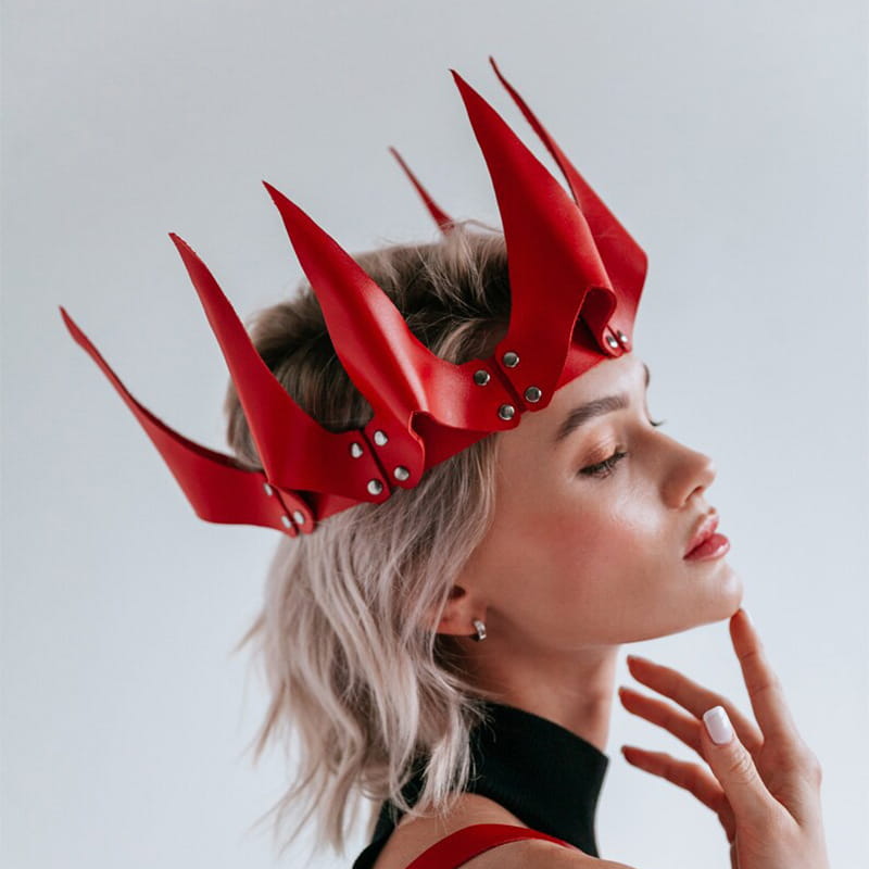 A striking red leather crown with sharp pointed spikes and silver rivets designed as performance accessories for stage costumes.