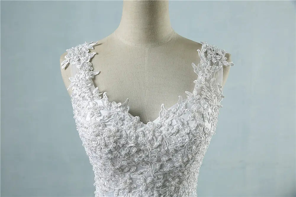 White lace wedding dress featuring intricate floral embroidery and delicate shoulder straps designed as a high waist wedding dress.