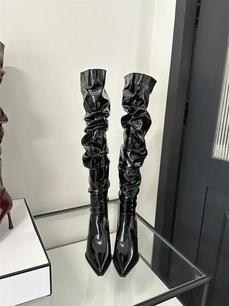 black patent leather thigh high boots with ruched glossy texture and pointed autumn stiletto heel showcasing heel pile style