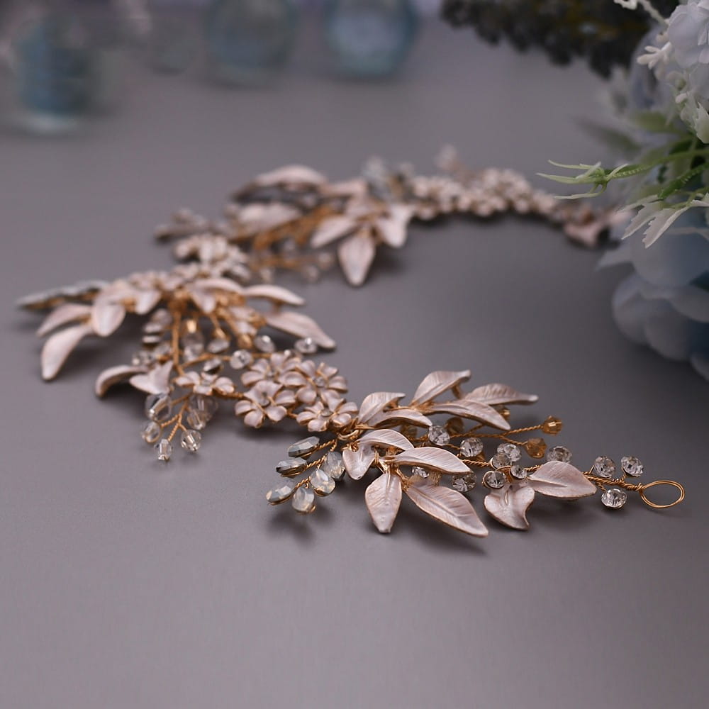 Elegant gold-toned bridal hair vine featuring delicate white enamel leaves and sparkling clear crystals made of rose gold alloy crystals japan hair accessories.
