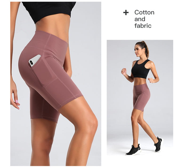 A pair of mauve high waist fitness gym cycling shorts made from cotton fabric with a side pocket holding a smartphone suitable as yoga pants.