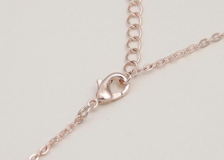Rose gold-toned lobster clasp attached to a delicate chain of a bride rhinestone pearl earrings necklace set.