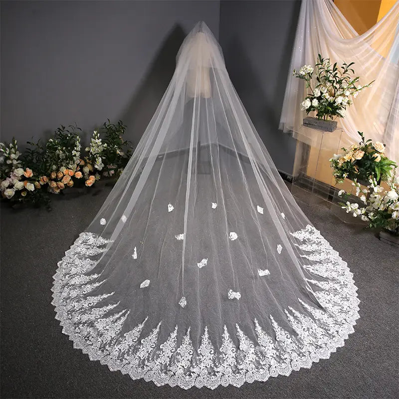 A delicate floor-length white lace wedding veil with intricate floral embroidery and a scalloped edge, perfect for complementing a lace wedding dress trailing design.