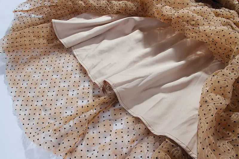 beige satin skirt with ruffled hem layered over sheer tan polka-dot lace fabric as part of a blush pink lace slim drawstring dress.