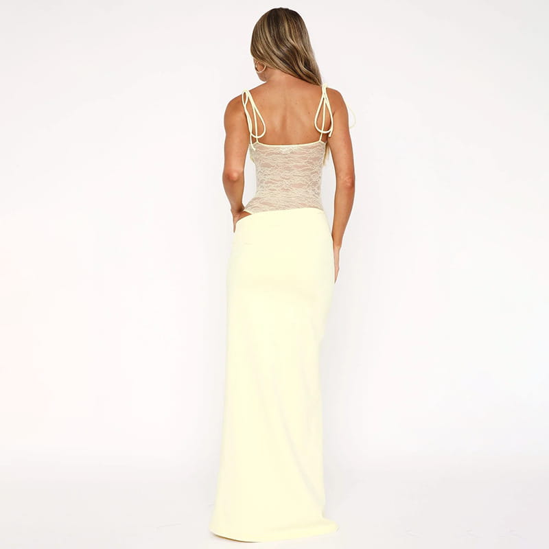 a woman wears a y2k lace suspender dress featuring an off-white lace top with thin tie-back straps and a flowing pale yellow skirt