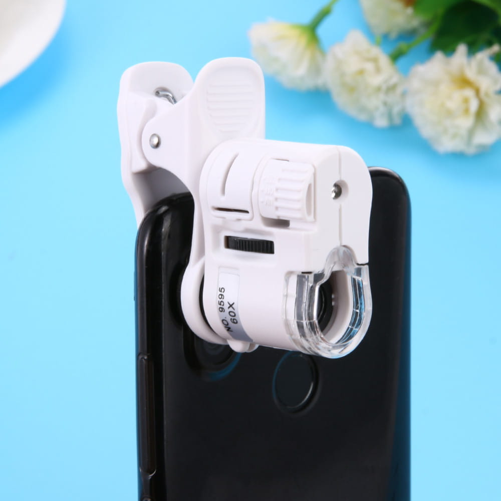 White clip-on digital microscope camera with clear lens, adjustable focus ring, and led light designed to attach to smartphones for close-up viewing.
